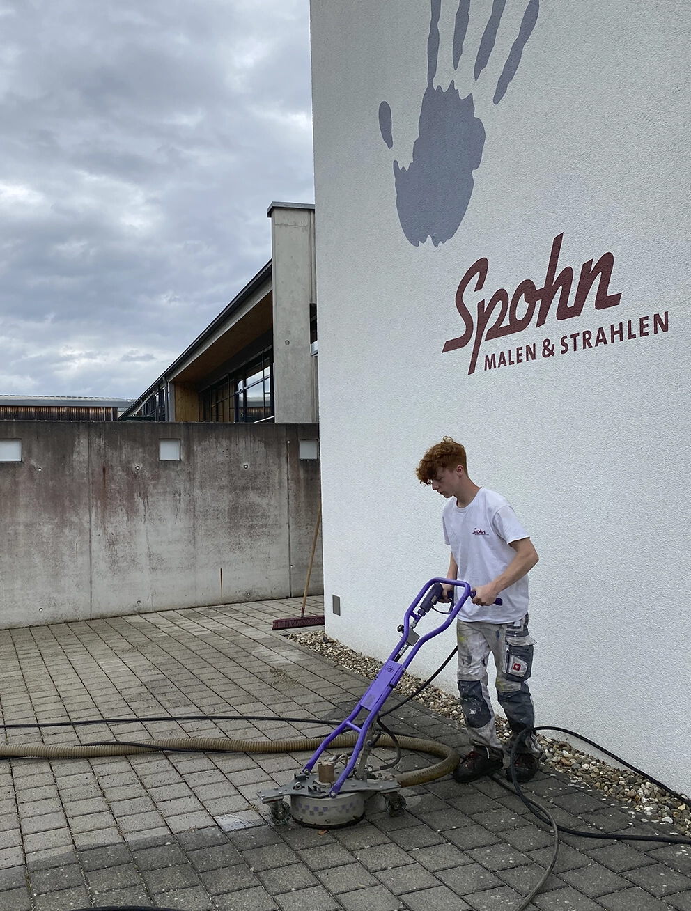 Mitarbeiter von Spohn Malen & Strahlen reinigt einen gepflasterten Hofbereich mit Spezialgerät für Outdoor Cleaning.