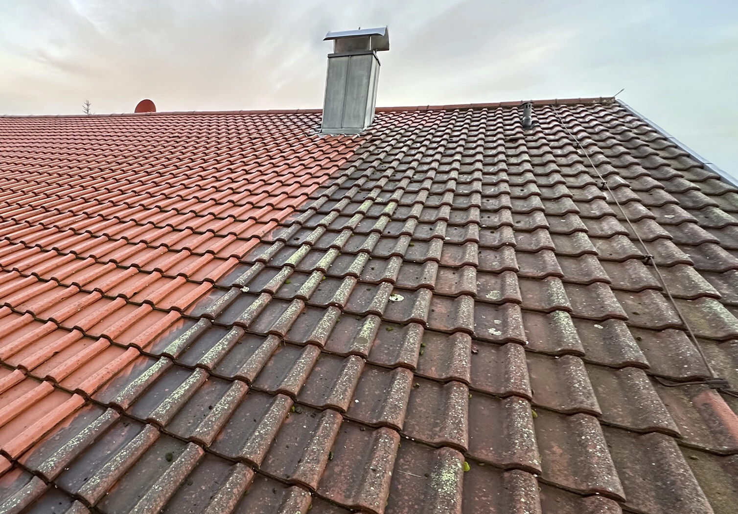 Schrägdach mit Dachziegeln im Vorher-Nachher-Vergleich: links gereinigt und deutlich heller, rechts stark verschmutzt mit Moos- und Algenbelag.